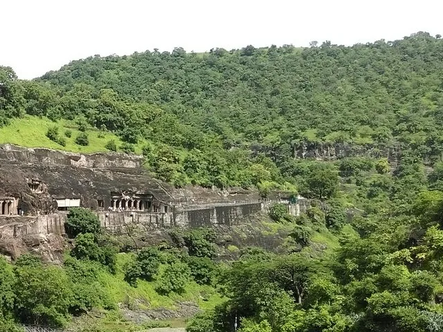 Panoramablick auf die Ajanta-Höhlen, die in den üppig grünen Hang gehauen sind.