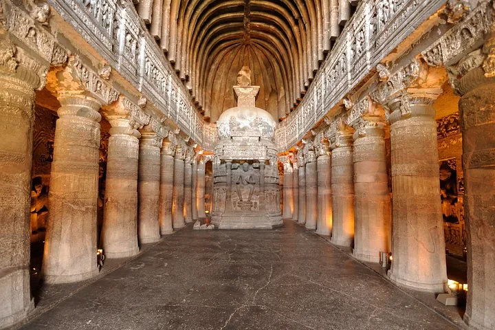 Intérieur majestueux d’une salle chaitya taillée dans la roche, avec piliers et un stupa central.